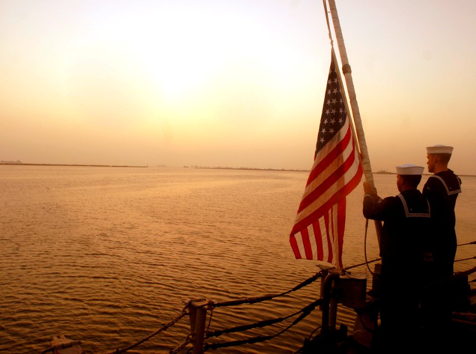 US Navy 090611-N-4879G-129 Operations Specialist Seaman Terry Wise and Seaman Joshua Nonoy lower the flag during evening colors aboard the guided missile frigate USS Doyle (FFG 39)