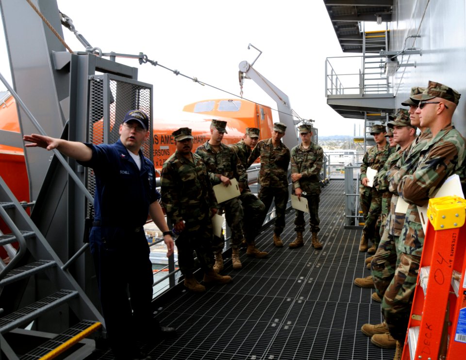 US Navy 090611-N-4973M-051 Operations Specialist 1st Class John Schill guides Seabees assigned to Amphibious Construction Battalion (ACB) 1 around life boats aboard the military sealift command dry cargo ammunition ship USNS Am