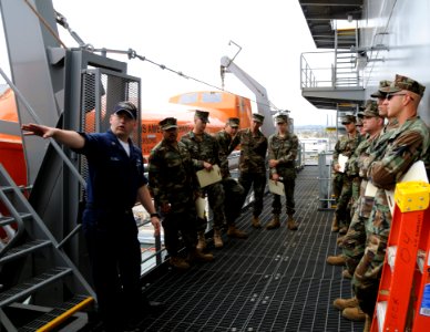 US Navy 090611-N-4973M-051 Operations Specialist 1st Class John Schill guides Seabees assigned to Amphibious Construction Battalion (ACB) 1 around life boats aboard the military sealift command dry cargo ammunition ship USNS Am