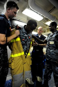 US Navy 090611-N-5242D-221 Damage Controlman 1st Class James Harry, Damage Controlman Fireman Jason King and Djiboutian Navy Sublieutenant Moussa Hanfare help Djiboutian Navy Cpl. Abdoullauder Issa remove a fire-fighting ensemb