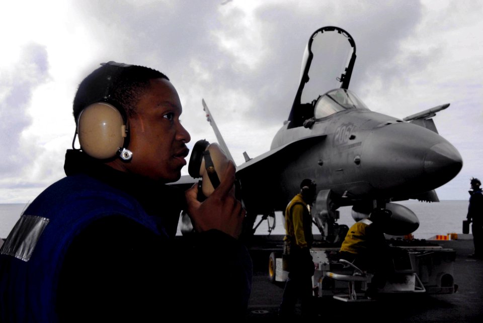 US Navy 090615-N-2475A-010 Aviation Boatswain's Mate (Handling) Airman Kelsey Gifford, from Augusta, Ga., communicates with hangar deck control while hangar bay personnel transfer a F-A-18C Hornet