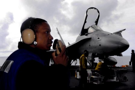 US Navy 090615-N-2475A-010 Aviation Boatswain's Mate (Handling) Airman Kelsey Gifford, from Augusta, Ga., communicates with hangar deck control while hangar bay personnel transfer a F-A-18C Hornet photo