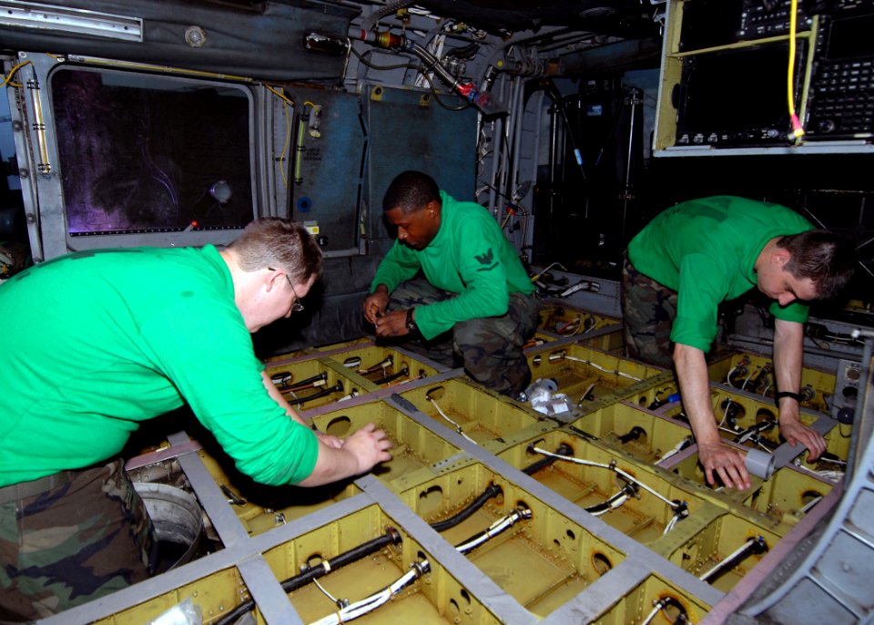 US Navy 090612-N-6720T-052 Sailors from the Chargers of Helicopter Anti-Submarine Squadron (HS) 14, apply insulating tape to the floor joists of an HH-60H Seahawk aboard USS George Washington (CVN 73)