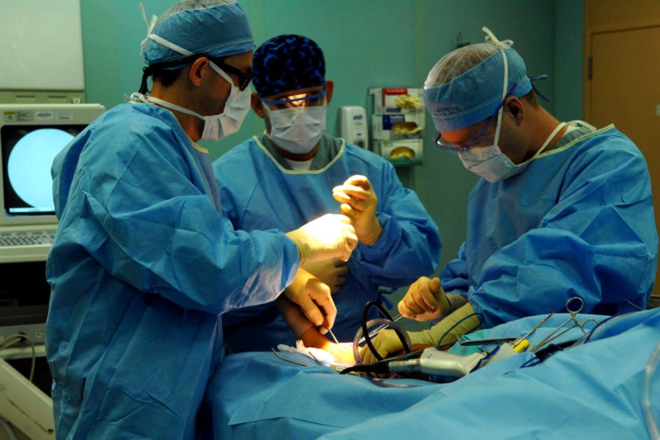 US Navy 090615-F-1333S-041 Joseph Slakey, removes a right tibial tumor from a young boy's leg during surgery aboard the Military Sealift Command hospital ship USNS Comfort (T-AH 20)