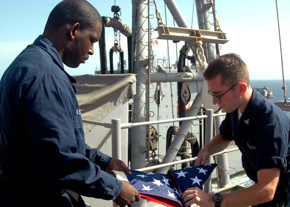 US Navy 090615-N-6410J-135 Amphibious assault ship USS Boxer (LHD 4) Quartermaster 3rd Class John Laseter and Quartermaster 3rd Class Casey Scott fold the American flag after flying it for a special detail