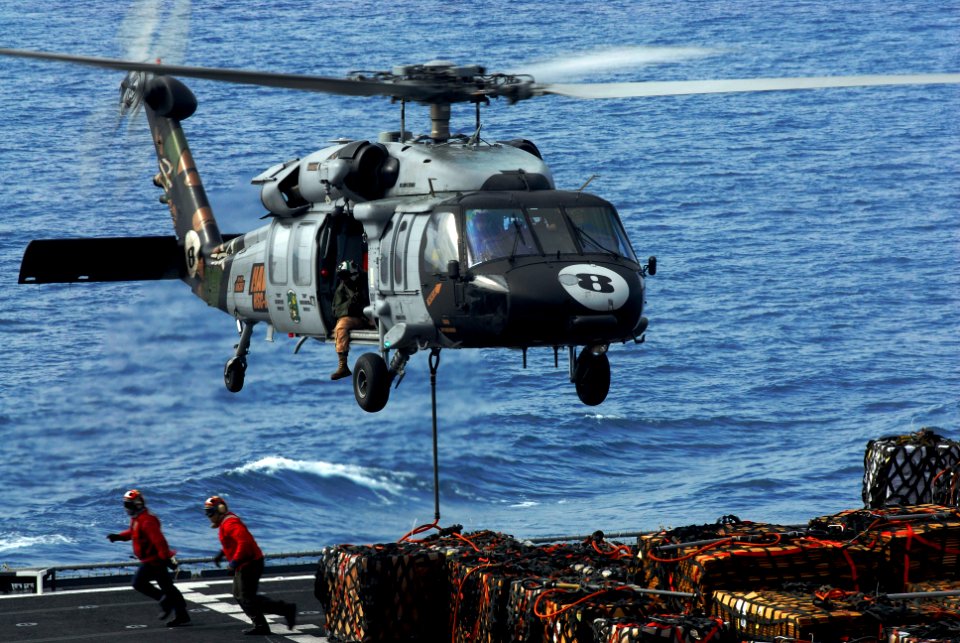 US Navy 090616-N-2475A-176 Sailors run clear of the landing area after attaching a cargo pendant to the bottom of an MH-60S Sea Hawk from the Eightballers of Helicopter Sea Combat Squadron (HSC) 8 as it hovers over the flight d