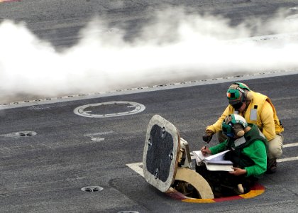 US Navy 090620-N-1062H-035 Shooter Lt. Marc Henderson studies the launching bulletin with Aviation Boatswain's Mate (Equipment) Airman Tia Brown on the flight deck of the aircraft carrier USS George Washington (CVN 73)