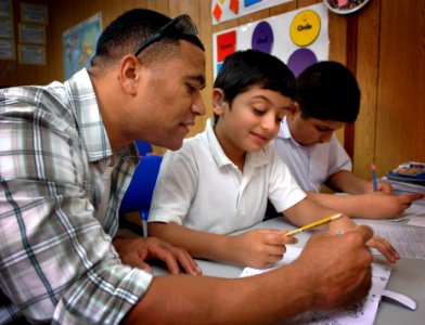 US Navy 090617-N-8053S-088 Cryptological Technician (Technical) 1st Class Daryl Maynes, assigned to U.S. Naval Forces Central Command, helps a student with his math at the Regional Institute for Active Learning in Adliya, Bahra