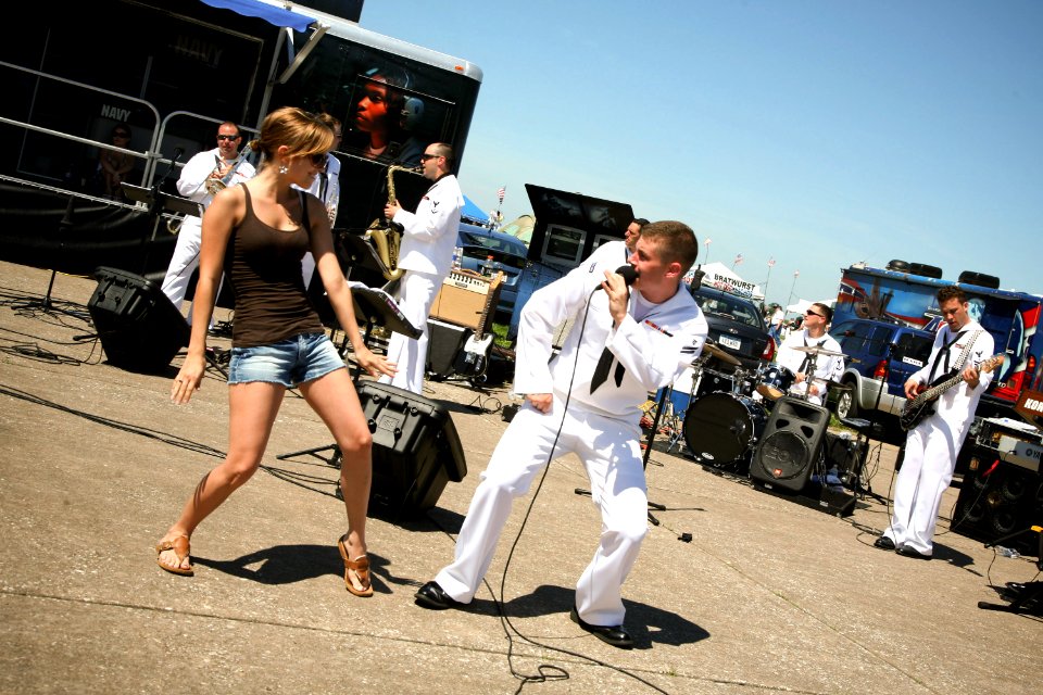 US Navy 090620-N-3271W-074 Musician Seaman Apprentice Steven Lamonica dances with an airshow patron during a performance by the U.S. Navy Band Great Lakes Horizon at the Quad Cities Airshow