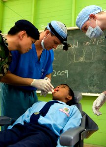 US Navy 090624-N-1722M-444 U.S. Navy dentist Lt. Brant Cullen, center, examines a student at Seberan Tayor Primary School