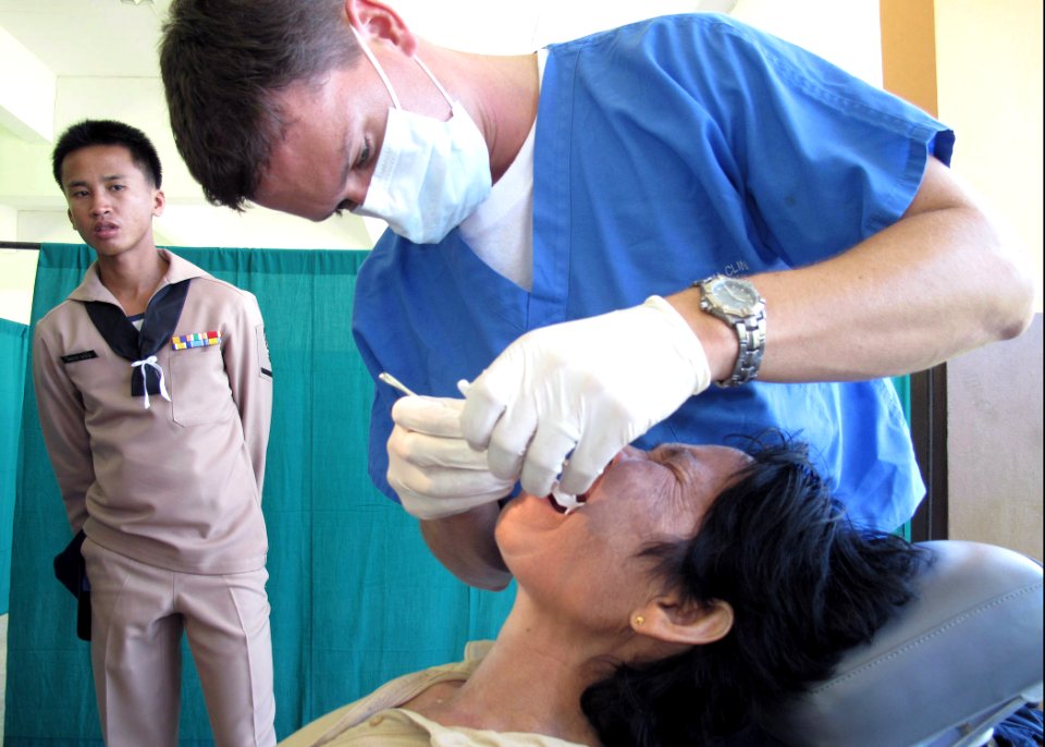 US Navy 090710-N-8539M-237 Lt. Brandt Cullen, dental officer aboard the dock landing ship USS Harpers Ferry (LSD 49), extracts a painful tooth from a Thai patient during a medical civic action program at Kiriparawanawan School