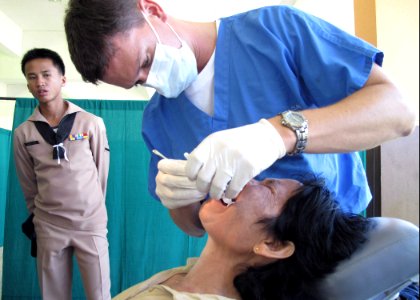 US Navy 090710-N-8539M-237 Lt. Brandt Cullen, dental officer aboard the dock landing ship USS Harpers Ferry (LSD 49), extracts a painful tooth from a Thai patient during a medical civic action program at Kiriparawanawan School photo