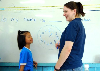 US Navy 090710-N-5207L-141 Culinary Specialist 3rd Class Tyrney Fisher of the dock landing ship USS Harpers Ferry (LSD 49) helps teach English to a student at Ban Khao By Si School during a community relations project photo