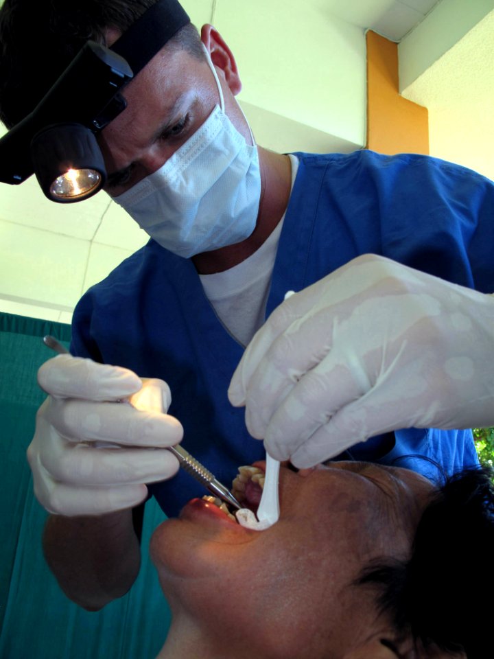 US Navy 090710-N-6770T-244 Lt. Brandt Cullen, dental officer aboard the dock landing ship USS Harpers Ferry (LSD 49), extracts a painful tooth from a Thai patient during a medical civic action program at Kiriparawanawan School