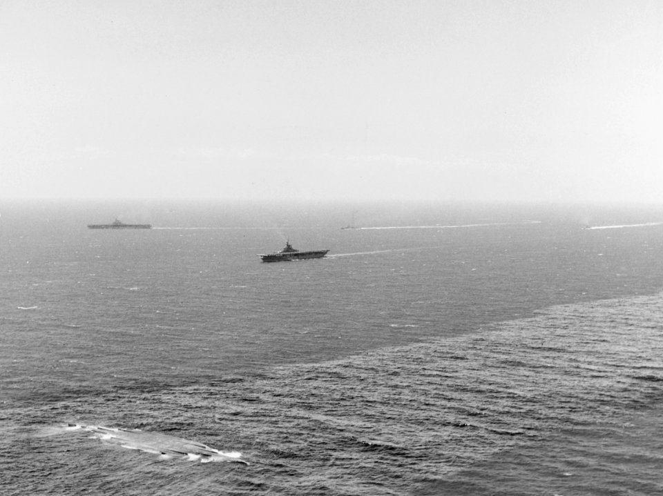 USS Boxer (CV-21) and USS Princeton (CV-37) steam past the capsized hull of USS New York (BB-34) off Hawaii on 8 July 1948