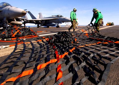 US Navy 090711-N-7282P-053 Storekeeper 3rd Class Liu Sin stretches out a cargo net before folding it for storage aboard the aircraft carrier USS George Washington (CVN 73) during a a vertical replenishment