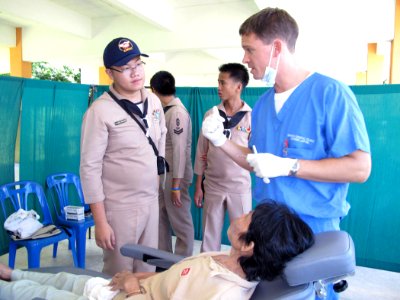 US Navy 090710-N-6770T-231 Lt. Brandt Cullen, dental officer aboard the dock landing ship USS Harpers Ferry (LSD 49), speaks with a Royal Thai Navy sailor during a medical civic action program at Kiriparawanawan School