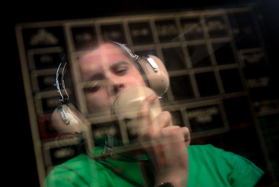 US Navy 090714-N-9132C-199 Aviation Boatswain's Mate (Equipment) 3rd Class Nathan Scharf communicates with arresting gear engine rooms as he looks at the arresting gear primary flight control screen