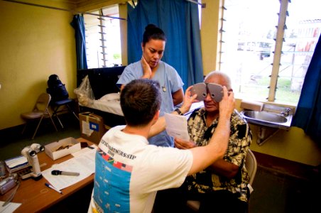 US Navy 090715-N-9689V-007 Lt. James David, an optometrist, conducts an eye exam with the aid of a Tongan interpreter for a local man during a Pacific Partnership 2009 during a Pacific Partnership 2009 medical civic action proj photo