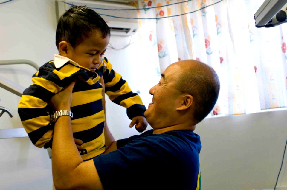 US Navy 090715-N-9689V-002 Cmdr. Joseph Yang, Pacific Partnership 2009 contingency dental officer-in-charge, lifts a child from a dental chair after a dental surgery during a medical civic action project at Niu'ui Hospital