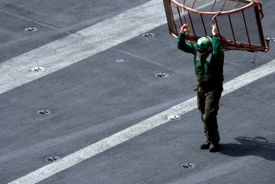 US Navy 090714-N-9132C-193 An aviation machinist's mate, assigned to the eagles of Strike Fighter Squadron 115 (VFA-115), carries a turn screen across the flight deck of the aircraft carrier USS Ronald Reagan (CVN 76)