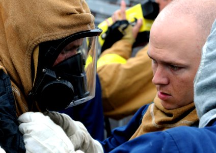 US Navy 090716-N-0807W-201 Damage control fire party members assigned to the mine warfare ship USS Avenger (MCM 1) help each other don their fire fighting ensemble during a main space fire drill