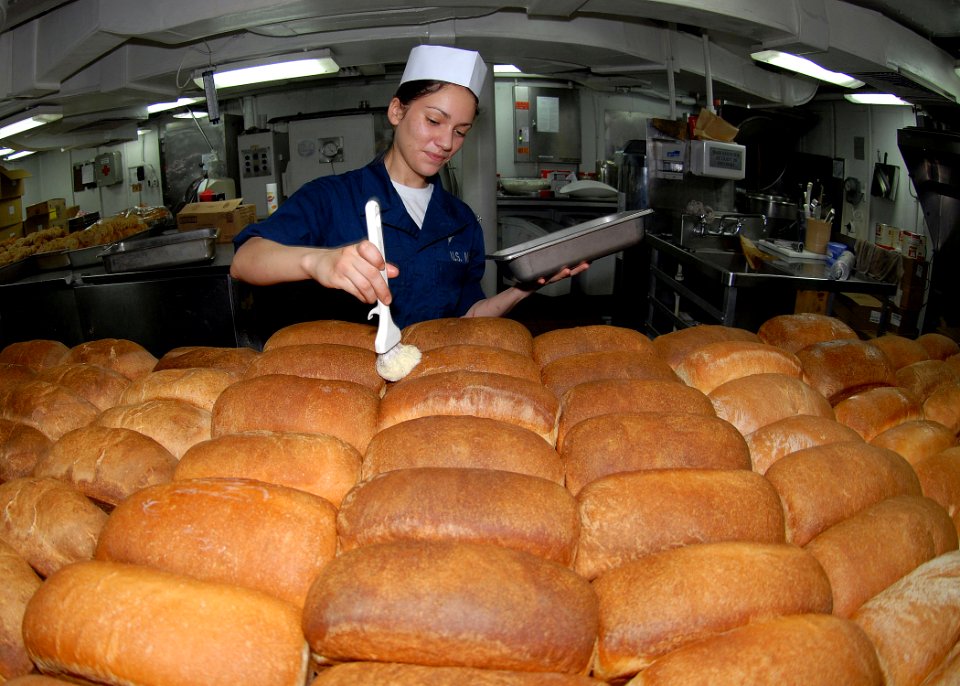 US Navy 090716-N-6720T-017 Culinary Specialist Seaman Samantha Garza butters loaves of fresh baked bread in the bakeshop aboard the aircraft carrier USS George Washington (CVN 73)