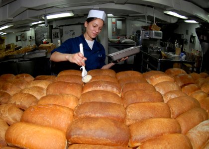 US Navy 090716-N-6720T-017 Culinary Specialist Seaman Samantha Garza butters loaves of fresh baked bread in the bakeshop aboard the aircraft carrier USS George Washington (CVN 73)