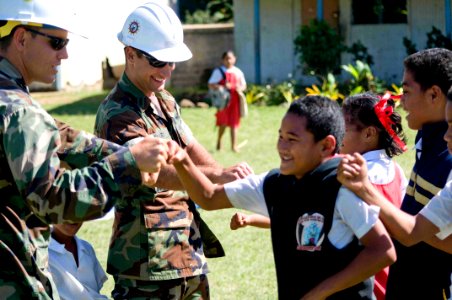US Navy 090717-N-9689V-011 Lt.j.g. Christian Auger of Naval Mobile Construction Battalion (NMCB) 1 and Lt.j.g. Shawn Talley of Amphibious Construction Battalion (ACB) 1 say good-bye to schoolchildren after playing a game of ba photo