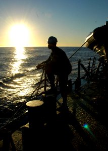 US Navy 090717-N-1655H-114 Boatswain's Mate 2nd Class Ronnie Graham waits for the order to lower a rigid hull inflatable boat from the guided-missile destroyer USS Arleigh Burke (DDG 51) photo