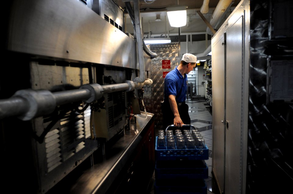 US Navy 090718-N-2344B-019 Aviation Electronics Technician Airman Adam Tucker restocks a cart of cups in the general mess aboard the aircraft carrier USS Ronald Reagan (CVN 76)