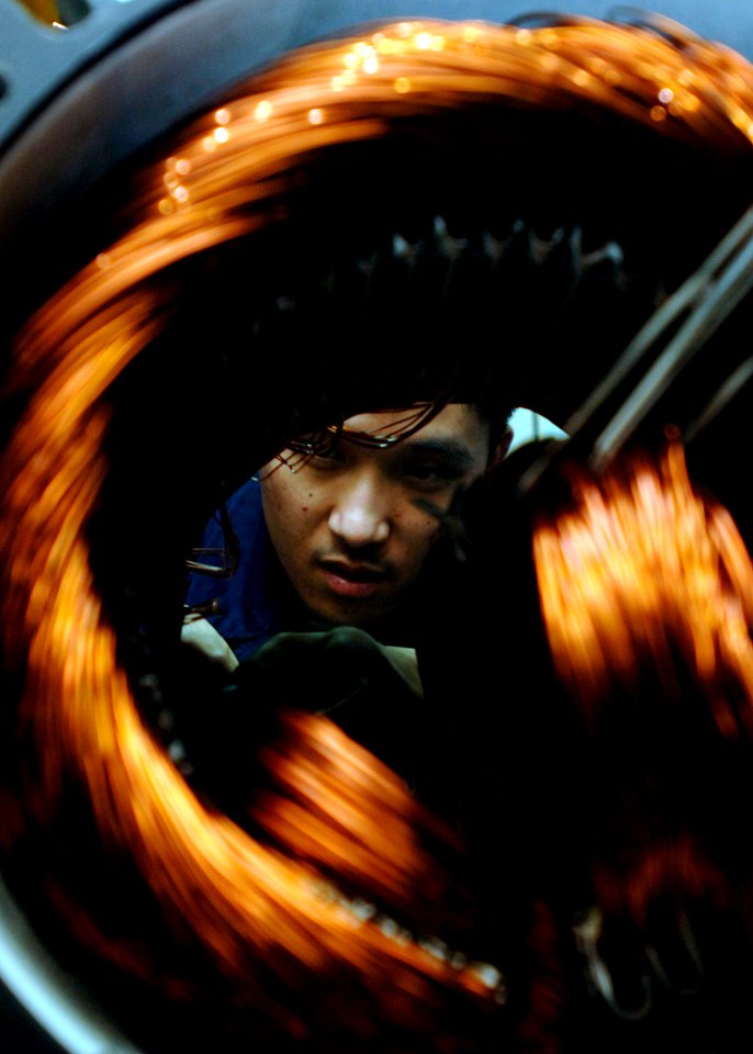 US Navy 090717-N-2013O-008 Electrician's Mate Fireman Ekkaphone Sayarath coils copper wire inside a brine pump while performing a pump rewind aboard the aircraft carrier USS George Washington (CVN 73)
