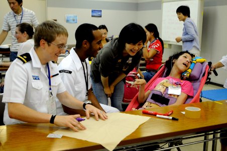 US Navy 090721-N-3830J-044 Ensign Kristina L. Gladstone, assigned to the amphibious command ship USS Blue Ridge (LCC 19), laughs as she helps make a flag for a child