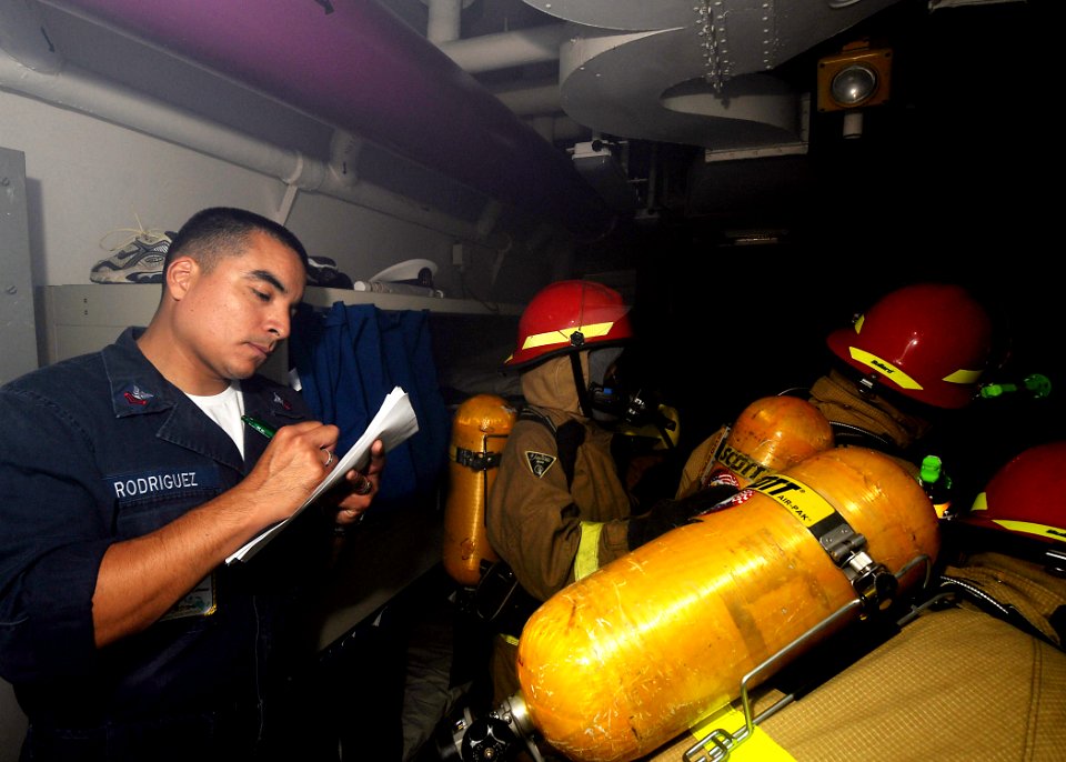 US Navy 090721-N-1062H-022 Damage Controlman 1st Class Chris Rodriguez grades hose team members on their ability to fight a simulated fire during a general quarters drill