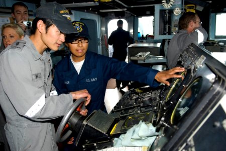 US Navy 090721-N-9123L-025 Boatswain's Mate Seaman Heather Connor from Anna, Texas explains functions of guided-missile destroyer USS McCampbell's (DDG 85) helm to Royal Australian Navy Able Seaman Eldric Ngo