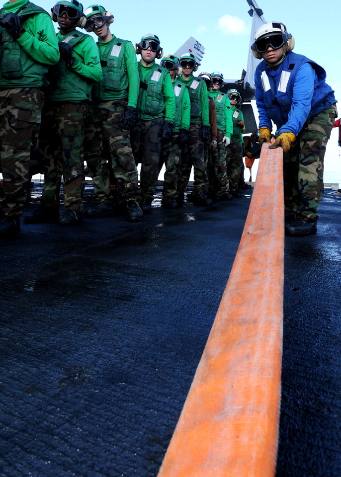 US Navy 090722-N-1062H-012 Aviation Boatswain's Mate (Handling) 3rd Class Rafael Caba fakes out a fire hose during a general quarters drill aboard the aircraft carrier USS George Washington (CVN 73)
