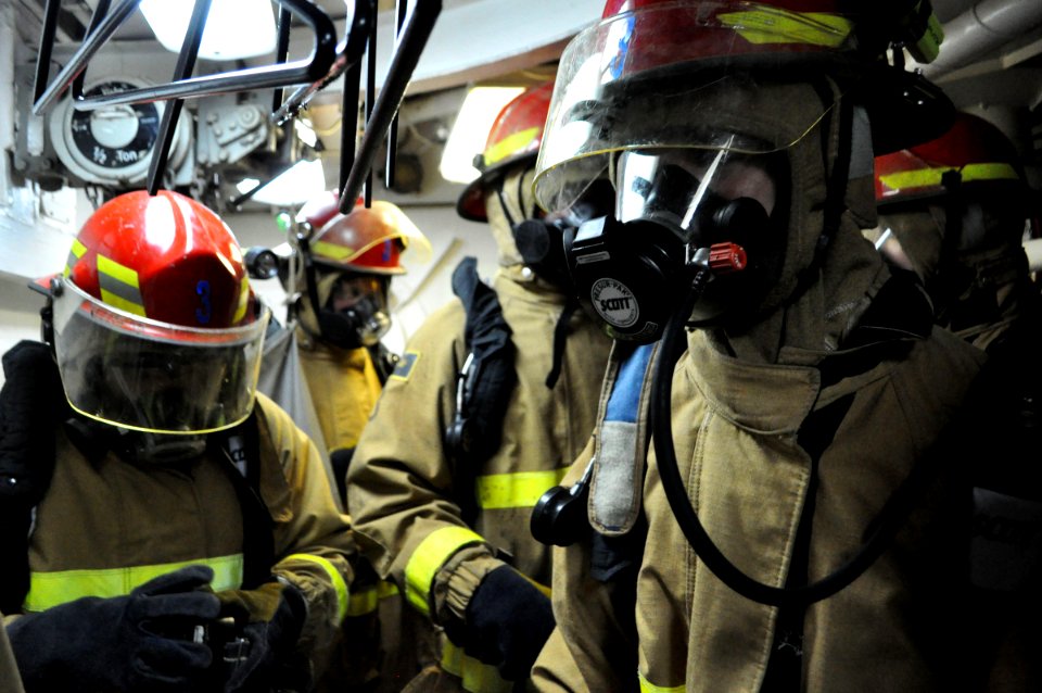 US Navy 090723-N-4124C-006 U.S. Naval Academy midshipmen in firefighting ensembles await instruction during a damage control familiarization walkthrough aboard the guided-missile cruiser USS Normandy (CG 60)