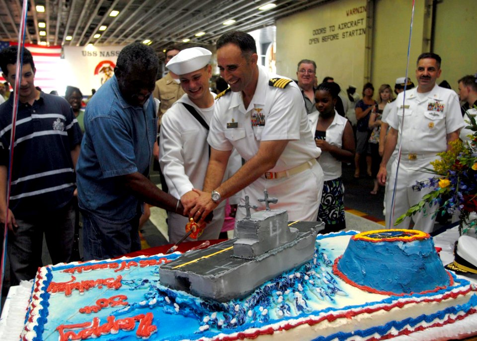 US Navy 090725-N-6439C-080 A former crew member, a crew member and the commanding officer cut a cake in the hangar bay of Nassau to celebrate the 30th anniversary of the ship's commissioning
