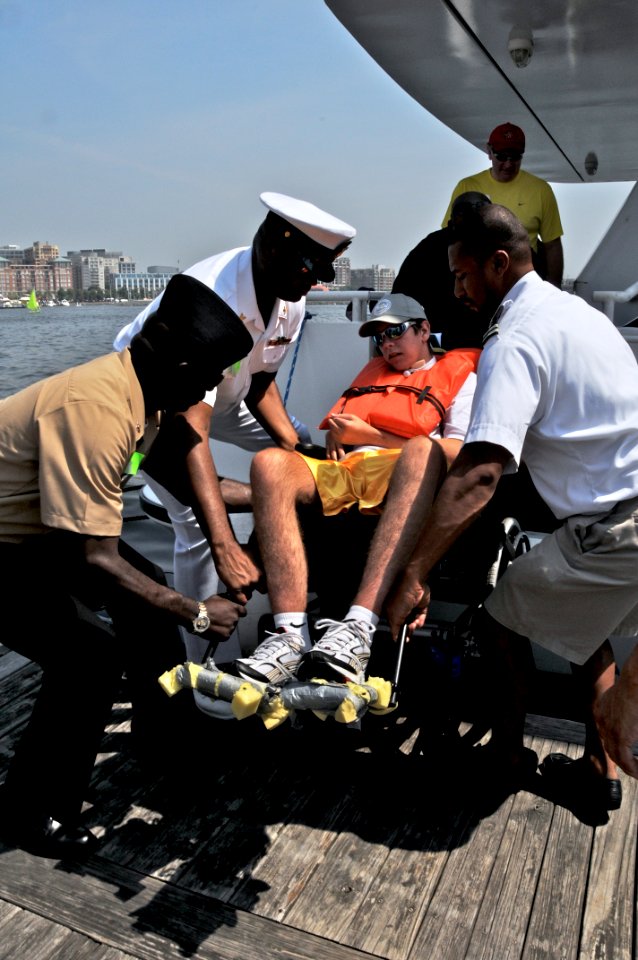 US Navy 090725-N-0807A-012 Aviation Structural Mechanic 2nd Class Orin Milo, Musician 1st Class Daryl Duff, and Jarid Wing lift James Becker after the 18th annual Easter Seals Cruise for Kids