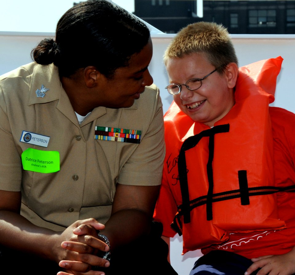 US Navy 090725-N-0807A-004 Yeoman 1st Class Datrice Peterson, assigned to Fleet Readiness Center Mid-Atlantic, Washington, chats with a child aboard the Pintail yacht during the 18th annual Easter Seals Cruise for Kids