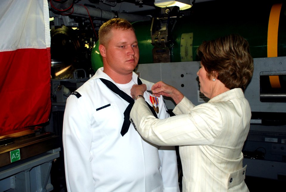US Navy 090731-N-3090M-060 Former first lady and ship's sponsor Laura Bush pins the submarine warfare device, or Dolphins, on the uniform of Machinists Mate 3rd Class Christopher Bragg