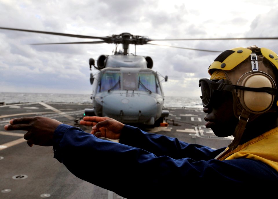 US Navy 090802-N-2638R-003 Gunner's Mate 3rd Class Saul Lowery, from Apopka, Fla., a landing signalman enlisted aboard Arleigh Burke-class guided-missile destroyer USS Mustin (DDG 89), signals to the pilot of an SH-60F Seahawk