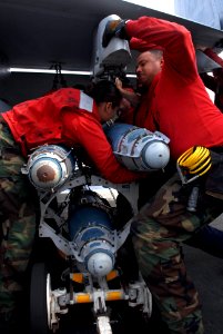 US Navy 090803-N-2600H-004 Aviation Ordnanceman 3rd Class Ira Baratt and Aviation Ordnanceman Airman Amy Landa, both assigned to the Black Aces of Strike Fighter Squadron (VFA) 41, lift an inert bomb into position under the win
