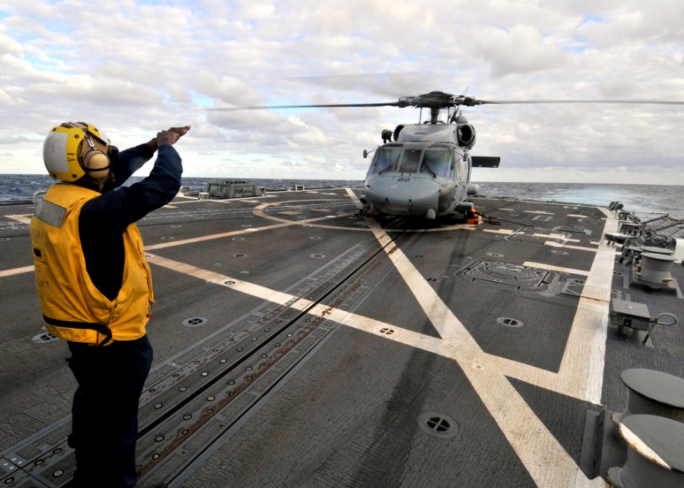 US Navy 090802-N-2638R-002 Gunner's Mate 3rd Class Saul Lowery, from Apopka, Fla., a landing signalman enlisted aboard the Arleigh Burke-class guided-missile destroyer USS Mustin (DDG 89), signals to the pilot of an SH-60F Seah