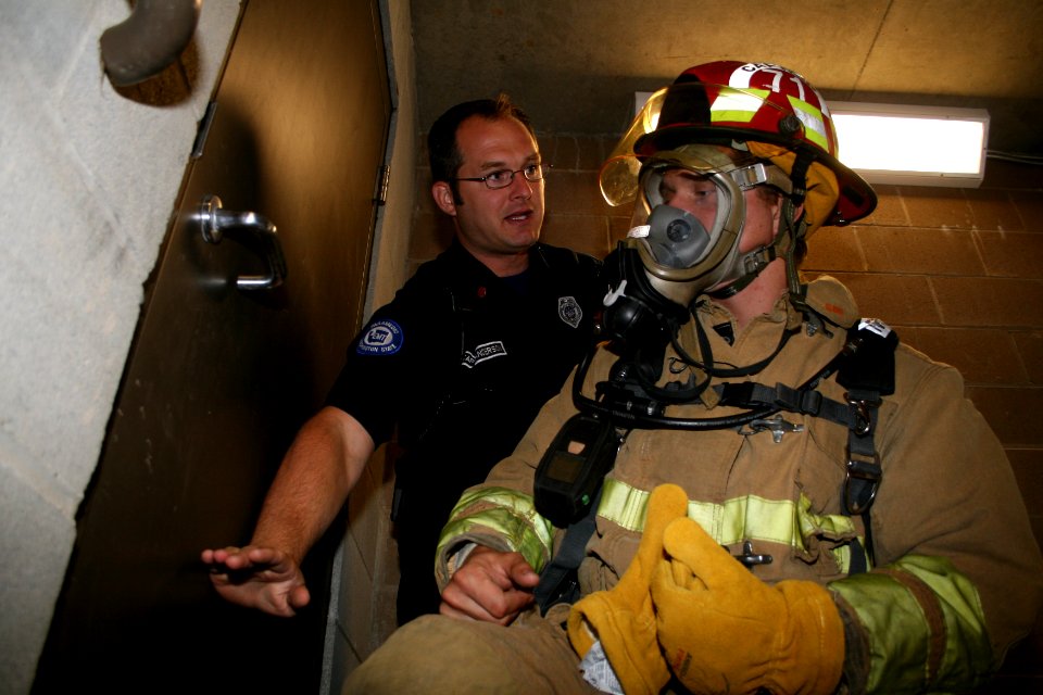 US Navy 090807-N-5366K-053 Police Capt. Shane Anderson explains how to feel for heat through a door when searching a burning building to Special Warfare Operator 1st Class (SEAL) Martin Lipinski at Poulsbo Fire Department