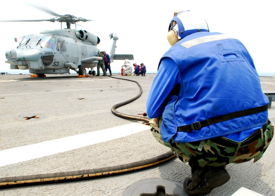 US Navy 090806-N-5207L-069 Seaman Steven Cameron, a member of the flight deck crew aboard the dock landing ship USS Harpers Ferry (LSD 49), helps refuel a SH-60B Sea Hawk helicopter