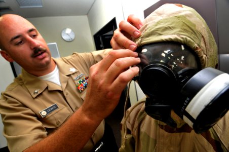 US Navy 090812-N-0807W-506 Hull Technician 1st Class Claude Lewis elps Ship's Serviceman 2nd Class Neil Mendoza as he dons a joint-service lightweight integrated suit technology chemical-protective ensemble