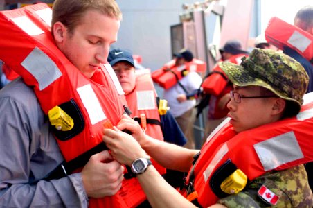 US Navy 090805-N-9689V-001 Canadian Army Capt. Jason Yee, a dentist embarked aboard the Military Sealift Command dry cargo-ammunition ship USNS Richard E. Byrd (T-AKE 4), shows Project HOPE pharmacy student Stephen Creasy how t