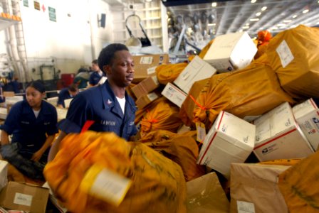 US Navy 090807-N-9132C-370 Information Systems Technician 3rd Class Calvin Lawson helps sort through 21,000 pounds of mail in the hangar bay of the aircraft carrier USS Ronald Reagan (CVN 76) photo