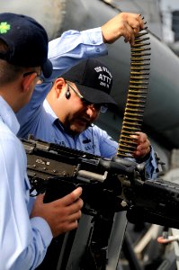 US Navy 090812-N-7498L-073 Anti-terrorism training team member, Gunner's Mate 1st Class Javier Villarreal, from Edinburg, Texas, loads an M-240 machine gun aboard the guided-missile destroyer USS O'Kane (DDG 77) as the ship pre